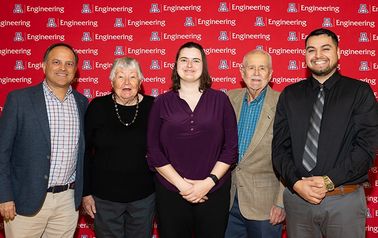 five people standing, smiling