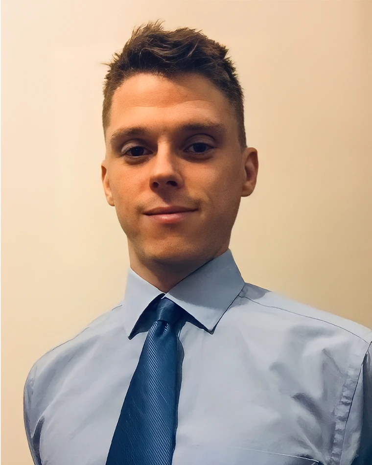 person with short, dark hair, wearing blue shirt and tie