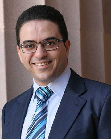 smiling man wearing blue suit, striped tie and glasses