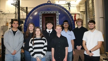 group of students, standing in front of lab equipment