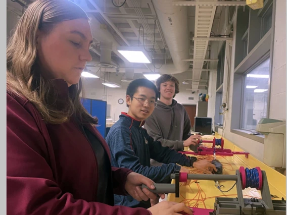 Team 25015 members (from left) Samantha Fisher, Joseph Lee and Will Zupancic adjust the cable tray mounts they designed and produced for making cables easier to manipulate in data centers.