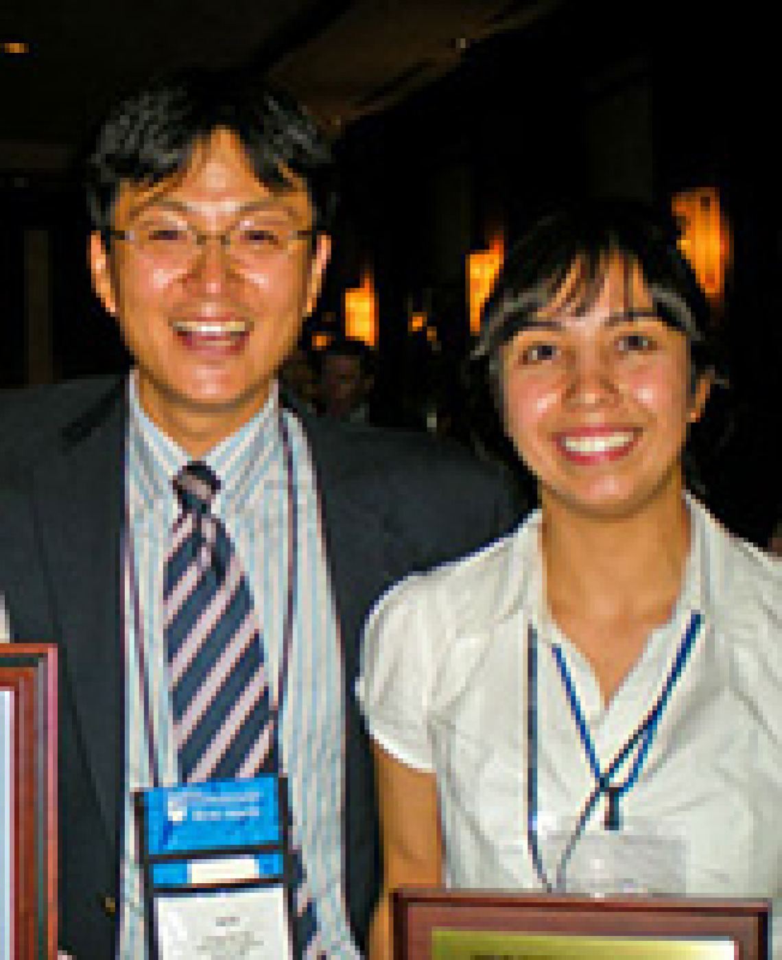 man and woman smiling, wearing lanyards