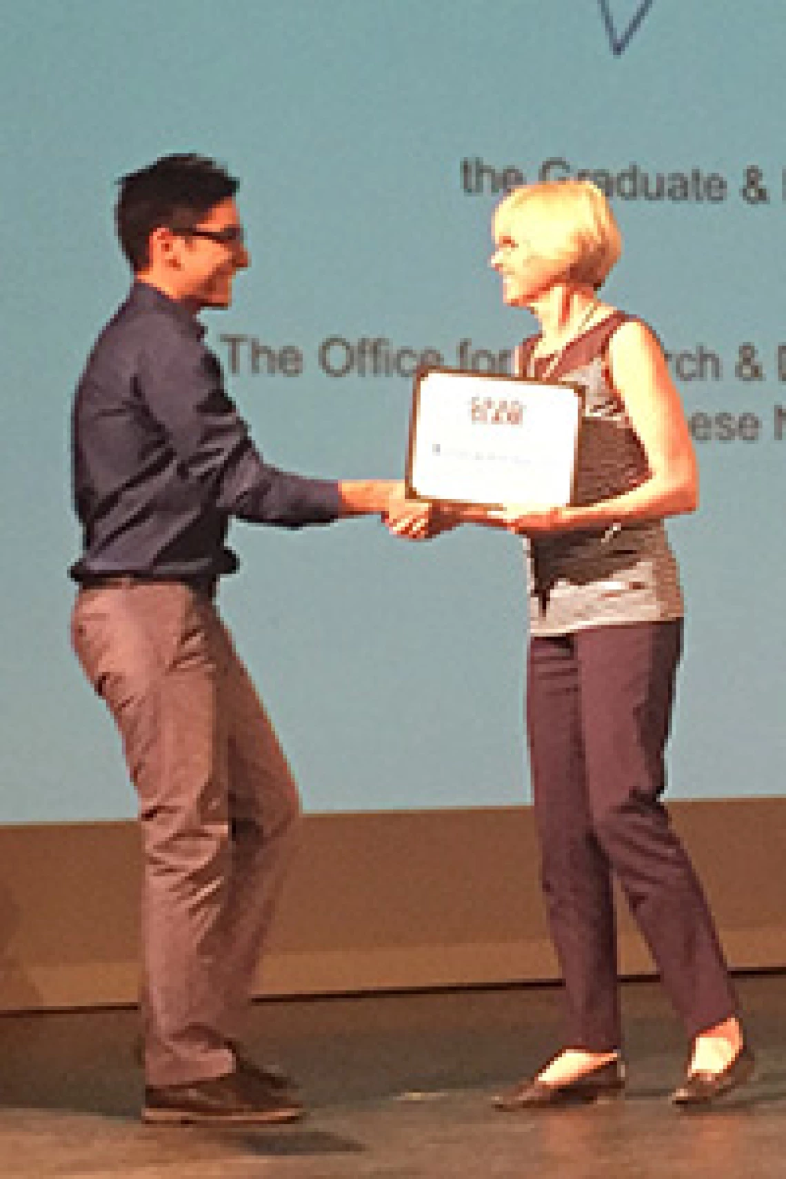 man and woman shaking hands, woman holding an award