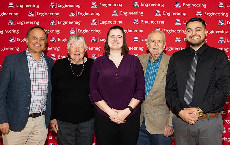 five people standing, smiling