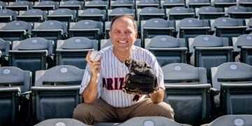 person seated on bench with baseball and baseball mit