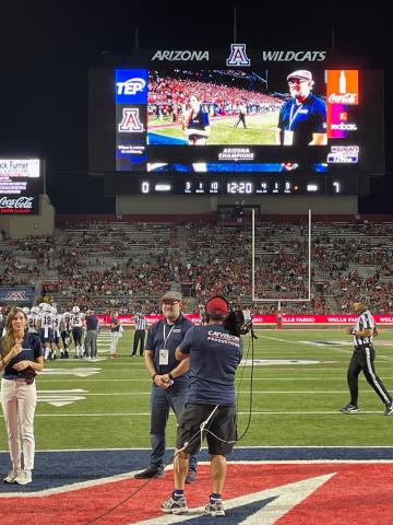 Brian Cunningham stands of a football field as he receives the Arizona Champion award. 