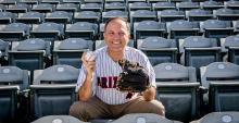 Ricardo Valerdi sits in the stands of a baseball stadium with a ball and mitt