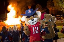 Wilbur and Wilma Wildcat posing for the camera in front of a bonfire