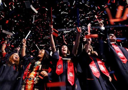 Graduates in caps and gowns throw confetti at UA Commencement