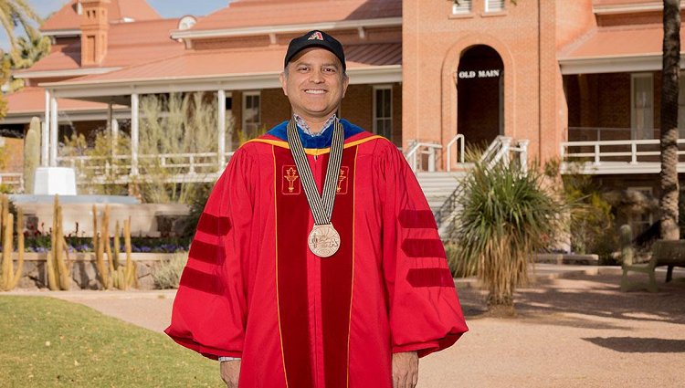 Ricardo Valerdi wearing a medallion in front of the University of Arizona Old Main building.